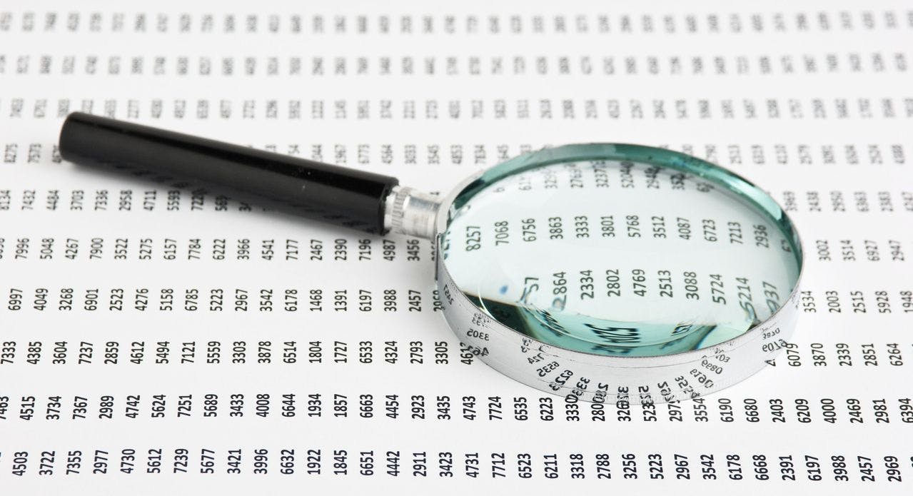 magnifying glass looking at a data spreadsheet